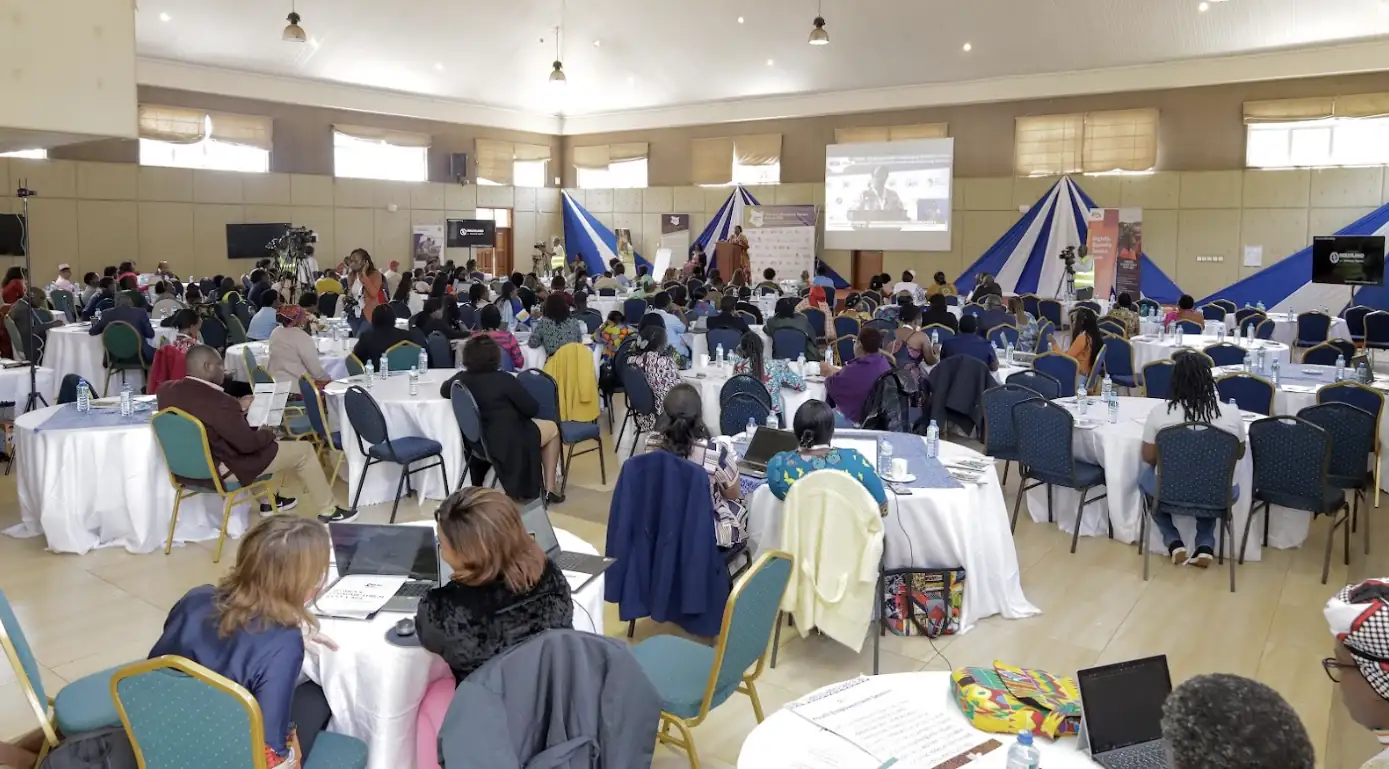 Wide shot of attendees seated at tables in a large corporate workshop