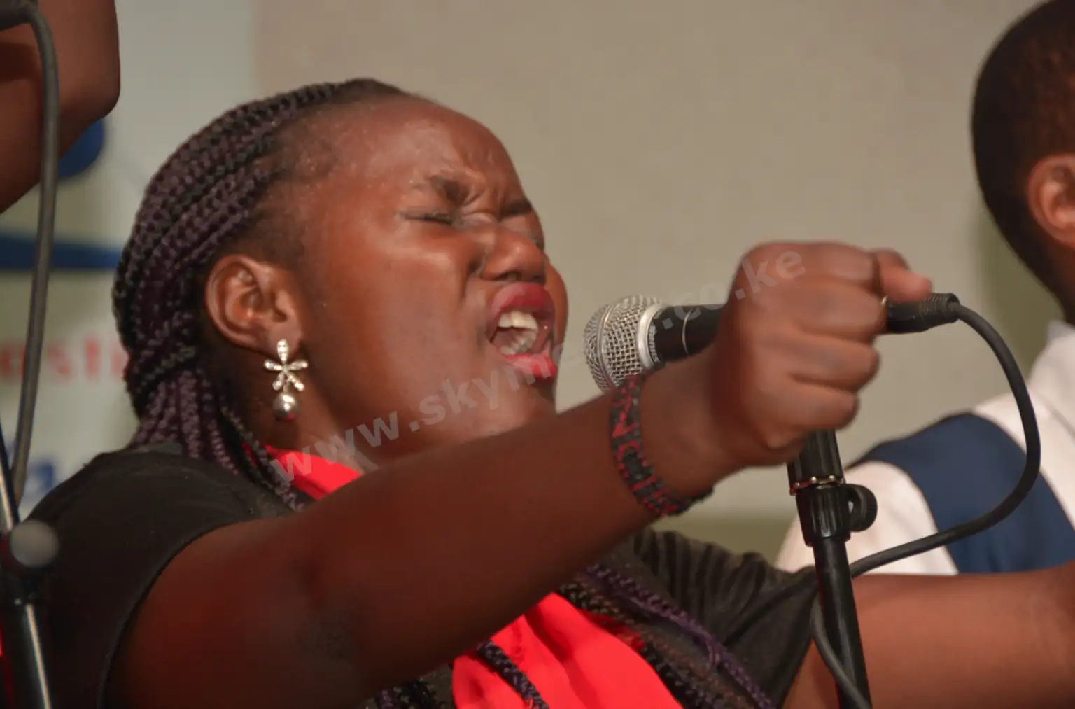 Woman singing with passion into a microphone at an indoor event